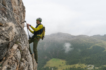 年轻有吸引力的男性登山者在陡峭和暴露通过 Ferrata 在南蒂罗尔巴迪亚在意大利白云岩