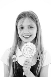 女孩的微笑与糖果隔离在白色。小孩子在棍子上微笑与糖果。快乐的孩子与漩涡焦糖。食物和甜点。享受糖果棒糖。饮食和节食