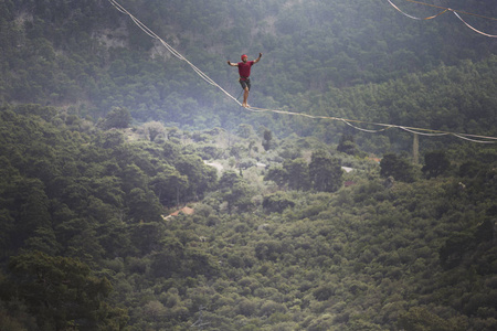 Highliner 在绳子上。Highline 在山的背景上。大自然的极限运动。在吊索上平衡。海拔平衡