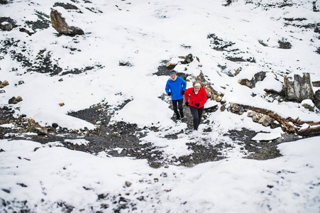 一对年长的夫妇在下雪的冬天自然上坡