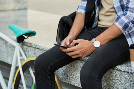 坐在大理石长凳上使用智能手机的自行车特写镜头