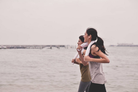 体育概念。美丽的女孩正在海滩上跑步。美丽的女孩是愉快的锻炼