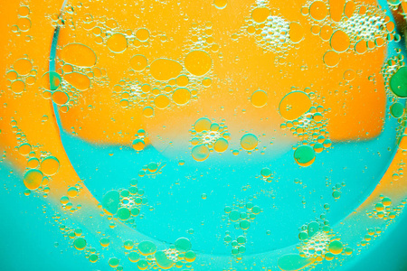 在橙蓝色背景的水中的油圈。文本的抽象背景