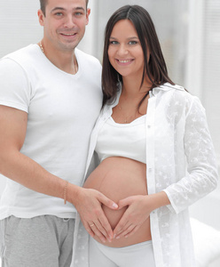 丈夫和怀孕的妻子，双手合十在他肚子上的一颗心的形状