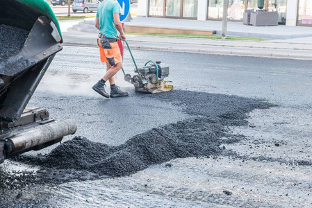 德国公路工人在公路上用振动夯捣紧沥青