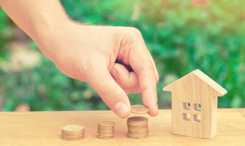 房地产投资概念。存钱买新家。木制房子和成堆的硬币从小到大。买, 租公寓。房屋物业按揭及税项
