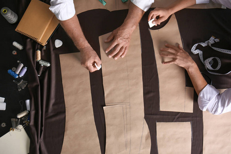 成熟的裁缝和他的助手工作室缝纫模式照片