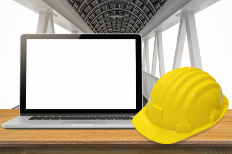 黄色安全帽和产业背景下，空白屏幕上桌上的笔记本电脑
