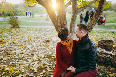 年轻浪漫幸福的情侣在爱的女人和男人的温暖的衣服牵手看着对方坐在