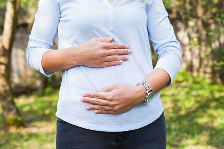 巴哥三个月照片关闭孕妇在户外散步时抱着腹部的照片.