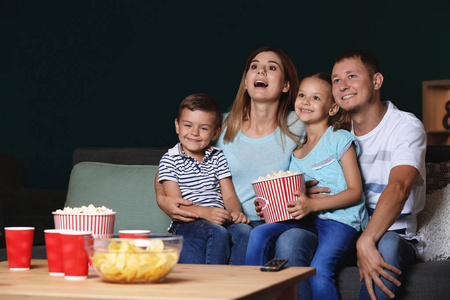 快乐的家庭在晚上看电视时吃爆米花