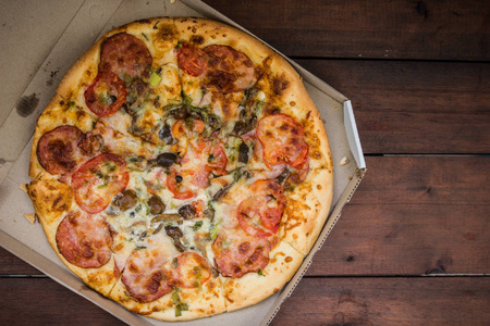 比萨的木质背景在乡村风格。意大利比萨从商店在一个纸板箱。木制背景下的简单食物