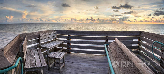 在佛罗里达州那不勒斯的日落时分, 长凳俯瞰着范德比尔特海滩的海洋。