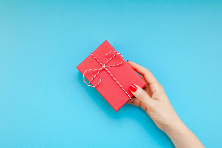 新年圣诞圣诞节情人节生日庆典妇女手红色指甲拿着礼物盒复制空间绿松石蓝彩色纸背景最小的风格。模板贺卡