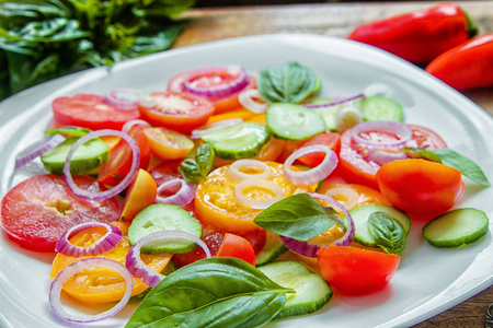 切下的传家宝西红柿, 脆黄瓜与切碎的红洋葱, 韭菜洒橄榄油和添加罗勒叶。所以夏天和新鲜的沙拉