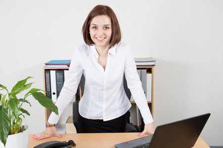 妇女使用膝上型电脑, 而站在她的办公桌