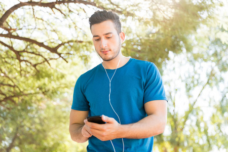 在公园里使用手机的帅哥慢跑听音乐