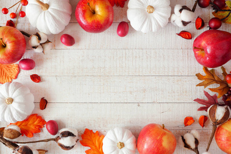 红色和白色主题秋季框架与苹果和南瓜在白色的木材背景。复制空间