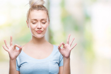 年轻的金发女人在孤立的背景下放松和微笑闭上眼睛做冥想手势用手指。瑜伽理念