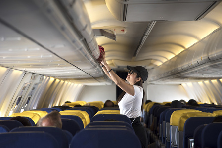 旅行者女人打开行李架上飞机图片