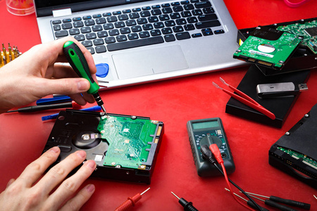 用特殊工具在红色桌子上修理一个修理工的硬盘驱动器的过程