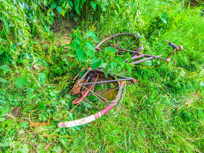 老倒下了生锈的自行车扔在公园里的草地上