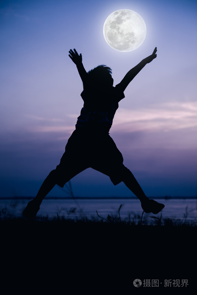 剪影的孩子享受和跳跃在滨江的背影
