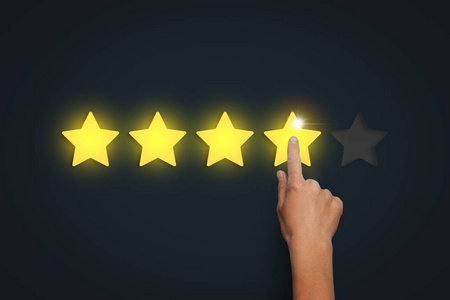 女性手在黑暗的背景下留下四颗星的等级在五可能.评估某事的概念照片