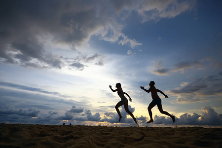 两名运动员沿着海滩奔跑的剪影, 暑假照片