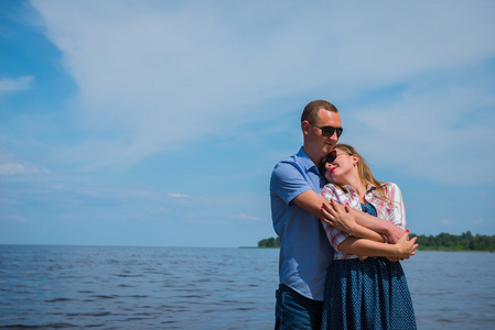 一对情侣站在河里,拥抱对方,蓝色天空背景, 阳光灿烂的日子, 广角, 长