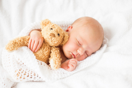 刚出生的婴儿女孩睡在一起的泰迪熊