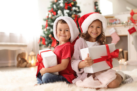 可爱的小朋友在圣诞老人的帽子与圣诞礼品盒在家里