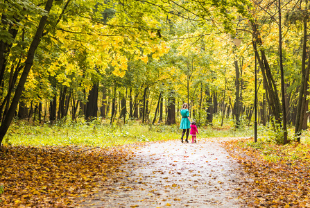 母亲和女儿走在秋天的公园后视图