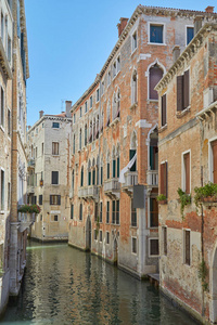 威尼斯运河与古老的建筑和房屋外墙在一个阳光明媚的日子在意大利