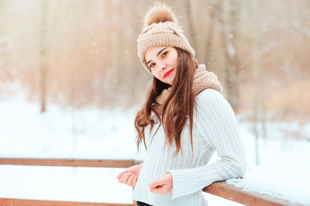 冬天的肖像快乐的年轻女子步行户外在雪地公园针织毛衣和帽子