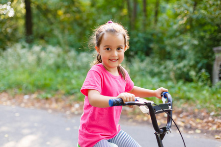 小女孩骑着自行车在城市公园