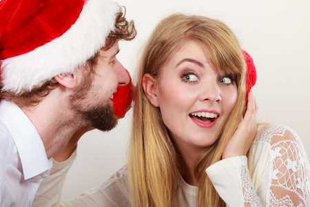 男人在女人耳边窃窃私语的圣诞老人帽子