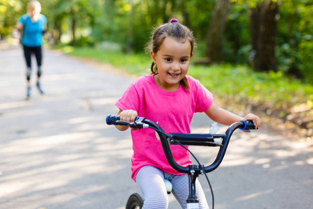 小女孩骑着自行车在城市公园