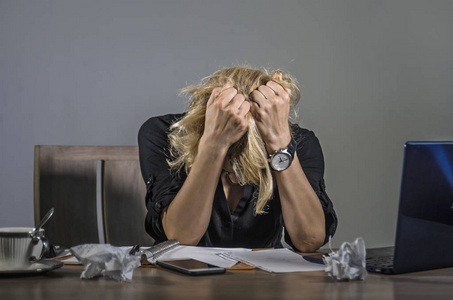 与笔记本电脑不堪重负的文件工作量覆盖她的脸绝望地遭受抑郁症照片