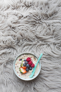 燕麦麦片粥与新鲜浆果的灰色毛皮背景, 顶部视图