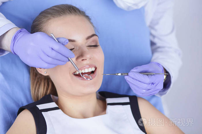 美丽的女孩在牙科椅子上检查牙医