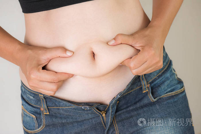 胖女人手捧着自己的腹部脂肪。女性饮食生活方式减少腹部和塑造健康胃肌肉概念