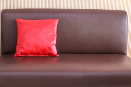 棕色皮革沙发上的一个红色枕头