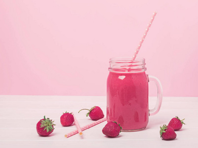 粉红色背景的罐子里的美味草莓冰沙