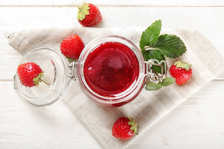 白色木桌上的美味草莓果酱玻璃罐