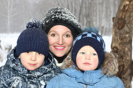 快乐的母亲和两个儿子在冬天的雪的时候微笑
