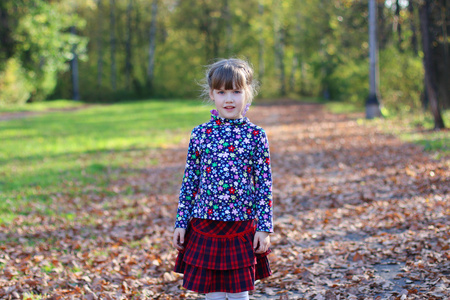 穿红裙子的可爱小女孩站在阳光灿烂的绿色公园，与博士