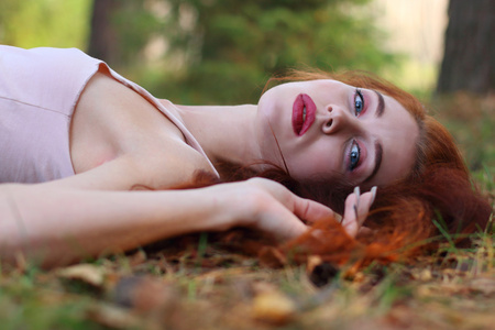 在泽西岛的红头发的漂亮女人躺在干树叶