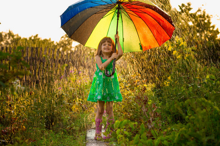 快乐的孩子女孩漫步与多彩多姿的雨伞下夏季雨