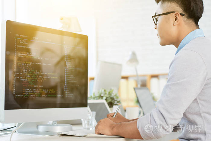 年轻的经理坐在桌前, 在办公室里做电脑工作.